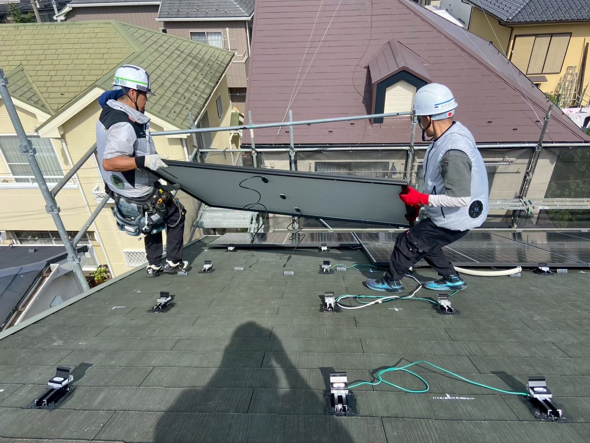 八王子市内の屋根で太陽光パネルを設置する自社スタッフ